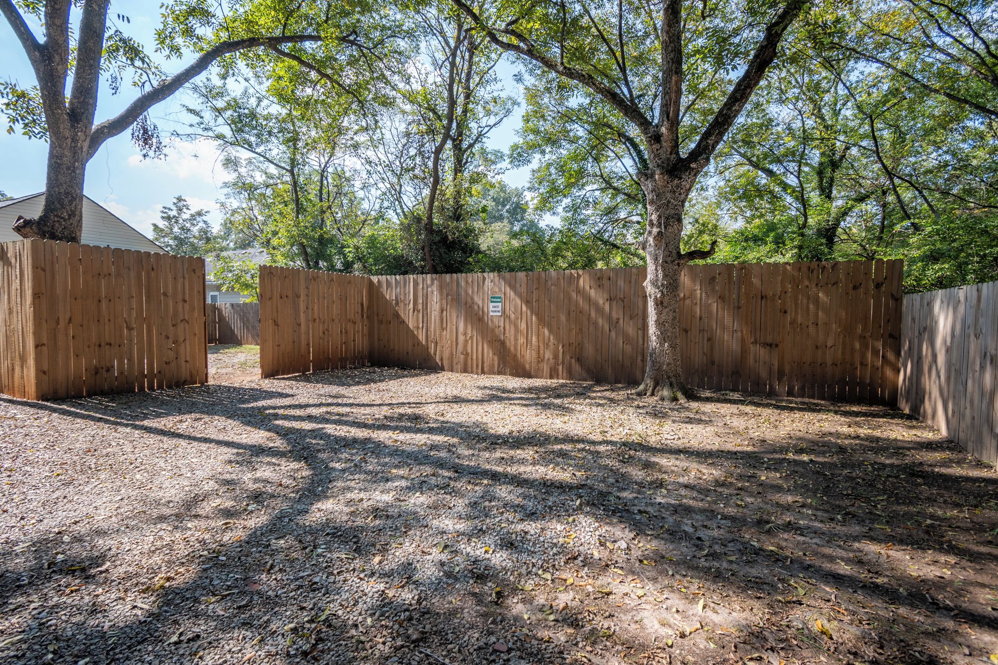 Un espace extérieur clos, avec un sol recouvert de gravier et entouré d’arbres.