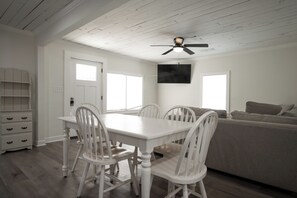 A dining area with a white table and chairs, a ceiling fan, and a large window.