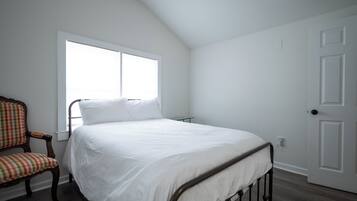Una camera da letto con un letto, una sedia, una finestra e una porta.