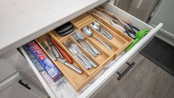 Un cajón de cocina con utensilios y una caja de azulejos.
