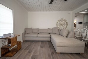 Ein modernes Wohnzimmer mit einer Eckcouch, einem Holztisch und einem Wandkunstwerk.