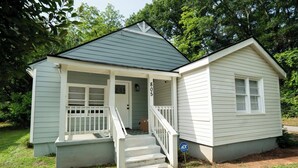 Een klein, gelijkvloers huis met een veranda en een voordeur.