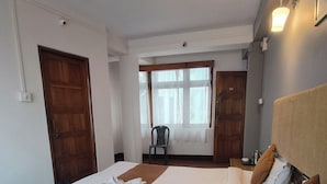 A hotel room with a large bed, a chair, and a desk. - Hotel Sakura Darjeeling (Darjeeling)