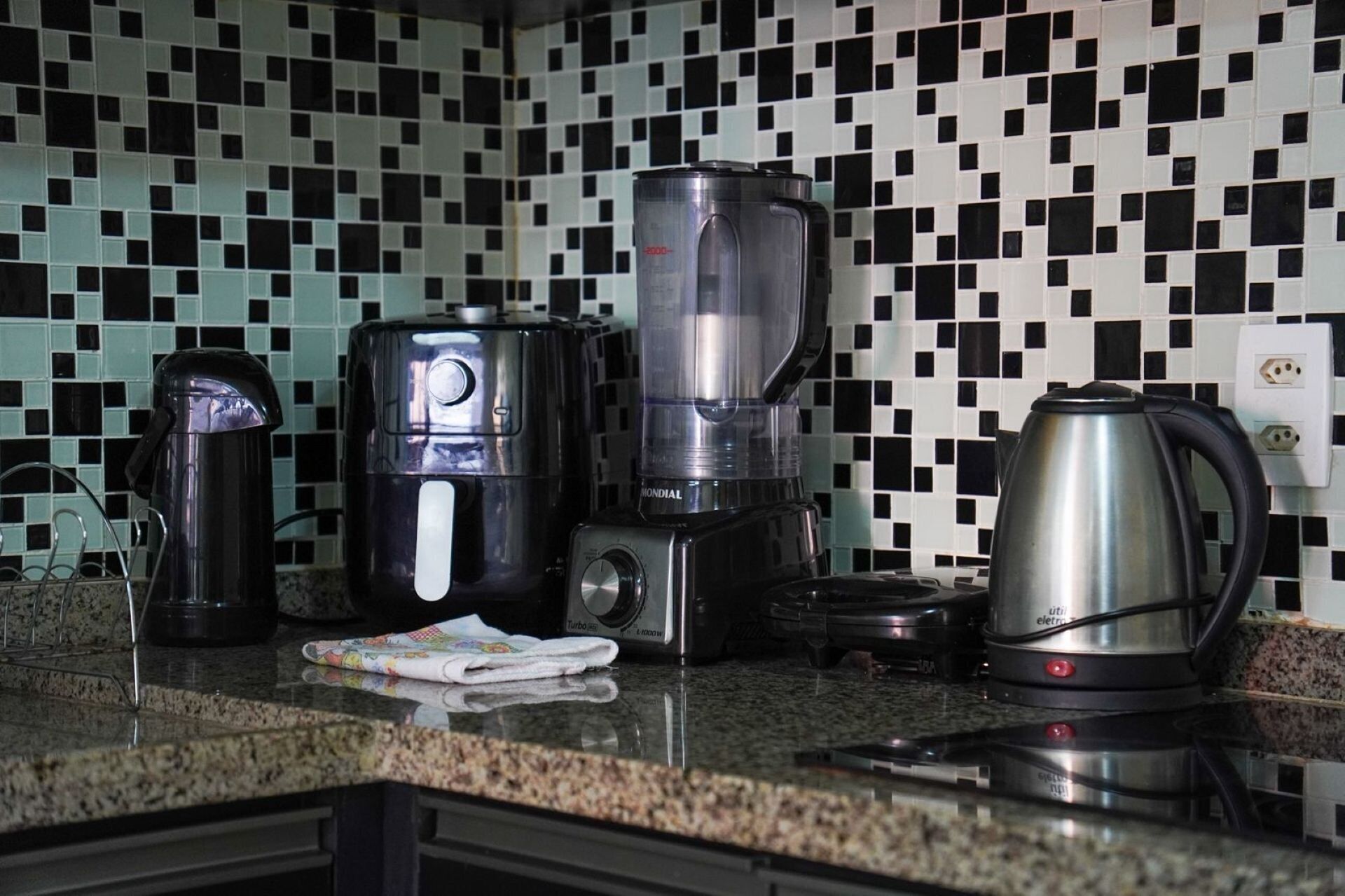 A kitchen with a coffee maker, a blender, and a kettle on the counter.
