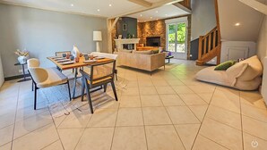 Amplia sala de estar con una mesa de comedor, sofá y cocina al fondo.