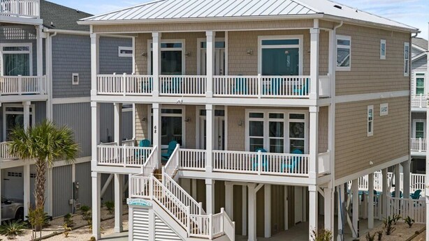 Une maison de plage à deux étages, dotée d’un balcon, d’un escalier et d’un petit espace piscine.