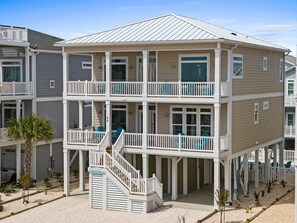 Une maison de plage à deux étages, dotée d’un balcon, d’un escalier et d’un petit espace piscine.