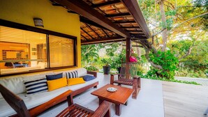 Un espacio al aire libre cubierto con un banco, una mesa y un sofá de madera con cojines.