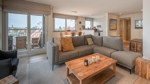 A spacious living area with a large sofa, a wooden coffee table, and a balcony with outdoor seating. - Apartment in Knokke Near the Beach (Knokke-Heist)