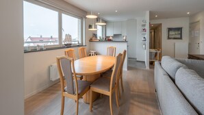 A modern apartment with a dining area, kitchen, and living space. - Apartment in Knokke Near the Beach (Knokke-Heist)