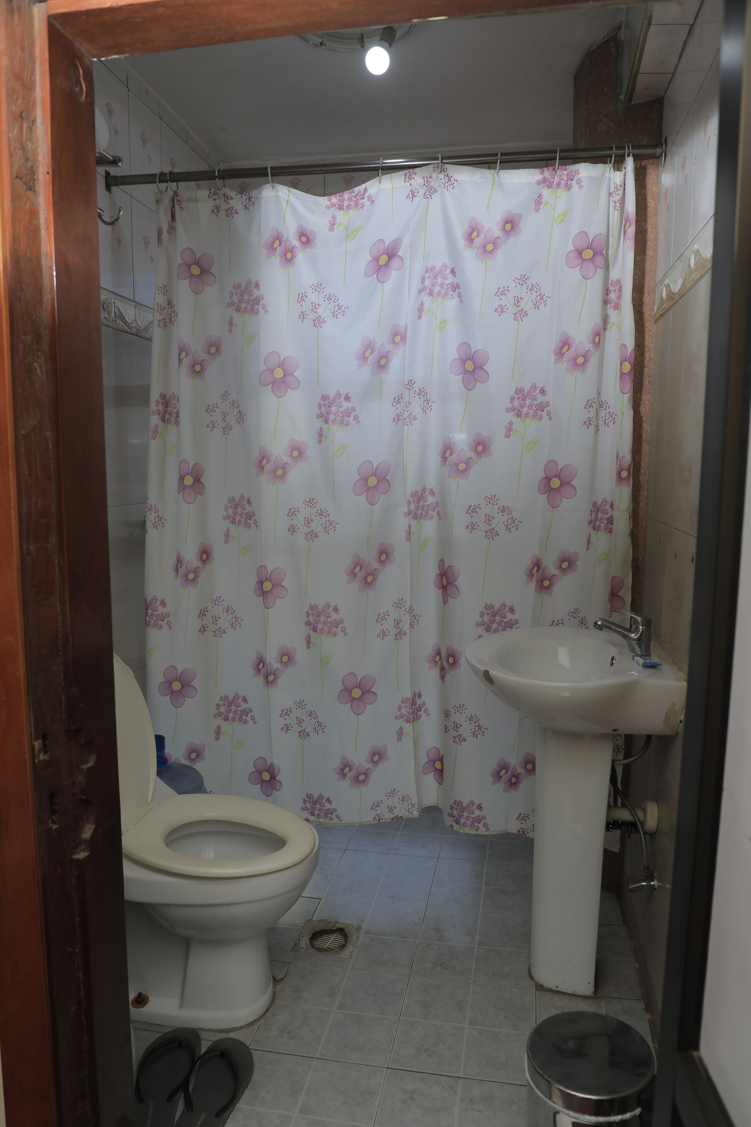 A bathroom with a toilet, sink, and shower curtain with a floral pattern.