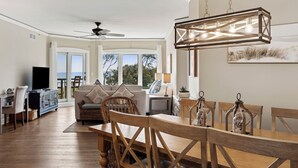 A spacious living area with a dining table, chairs, and a ceiling fan.