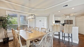 A dining area with a wooden table and chairs, a potted plant, and a hanging light fixture.