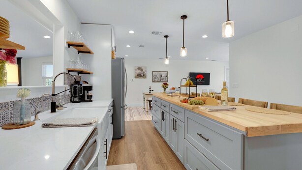 Una cocina moderna con una isla central, electrodomésticos integrados e iluminación colgante.