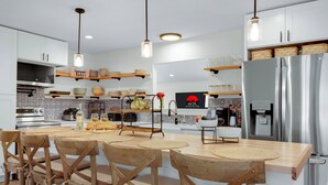 Una cocina moderna con sillas de madera, un refrigerador de acero inoxidable y una cafetera.