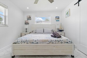 A bedroom with a bed, two bedside tables, a window, and wall decorations.