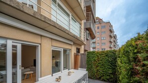 A modern apartment with a balcony, a dining area with a table and chairs, and a view of neighboring buildings. - Apartment in Knokke Near Duinbergen Beach (Knokke-Heist)