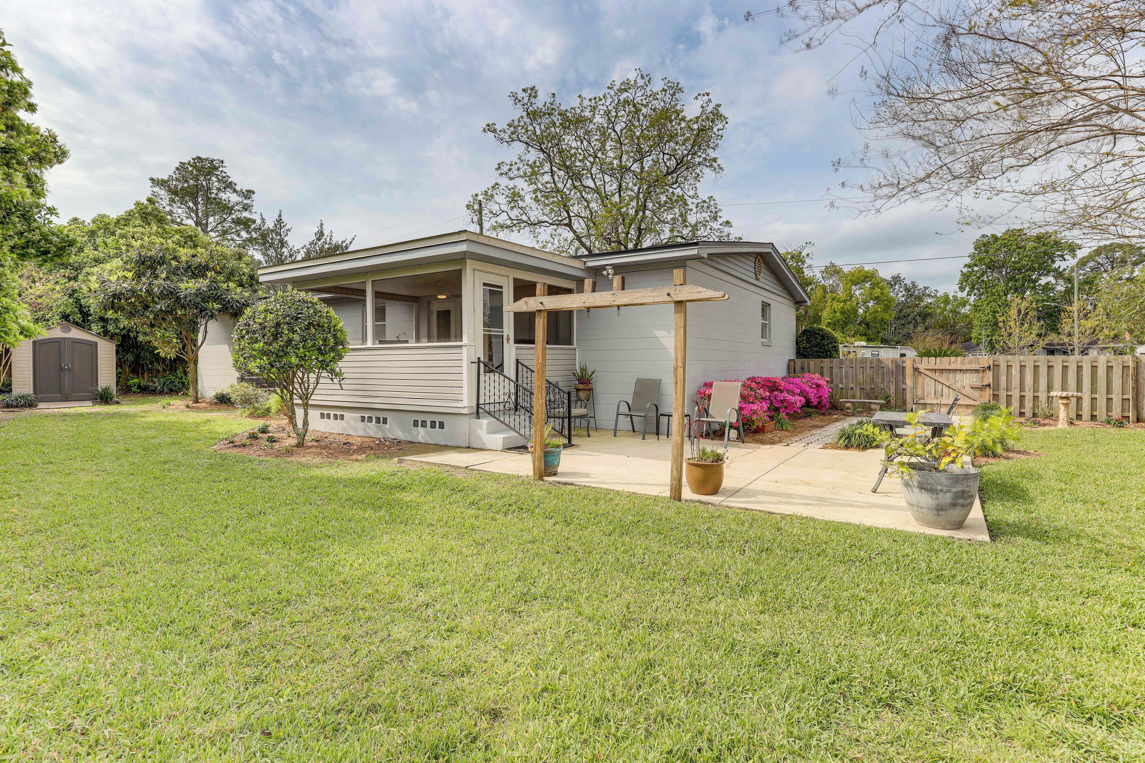 Une maison de plain-pied avec un patio couvert, un petit jardin devant et une clôture en bois.