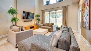 A spacious living room with a large sofa set, a coffee table, and two potted plants.