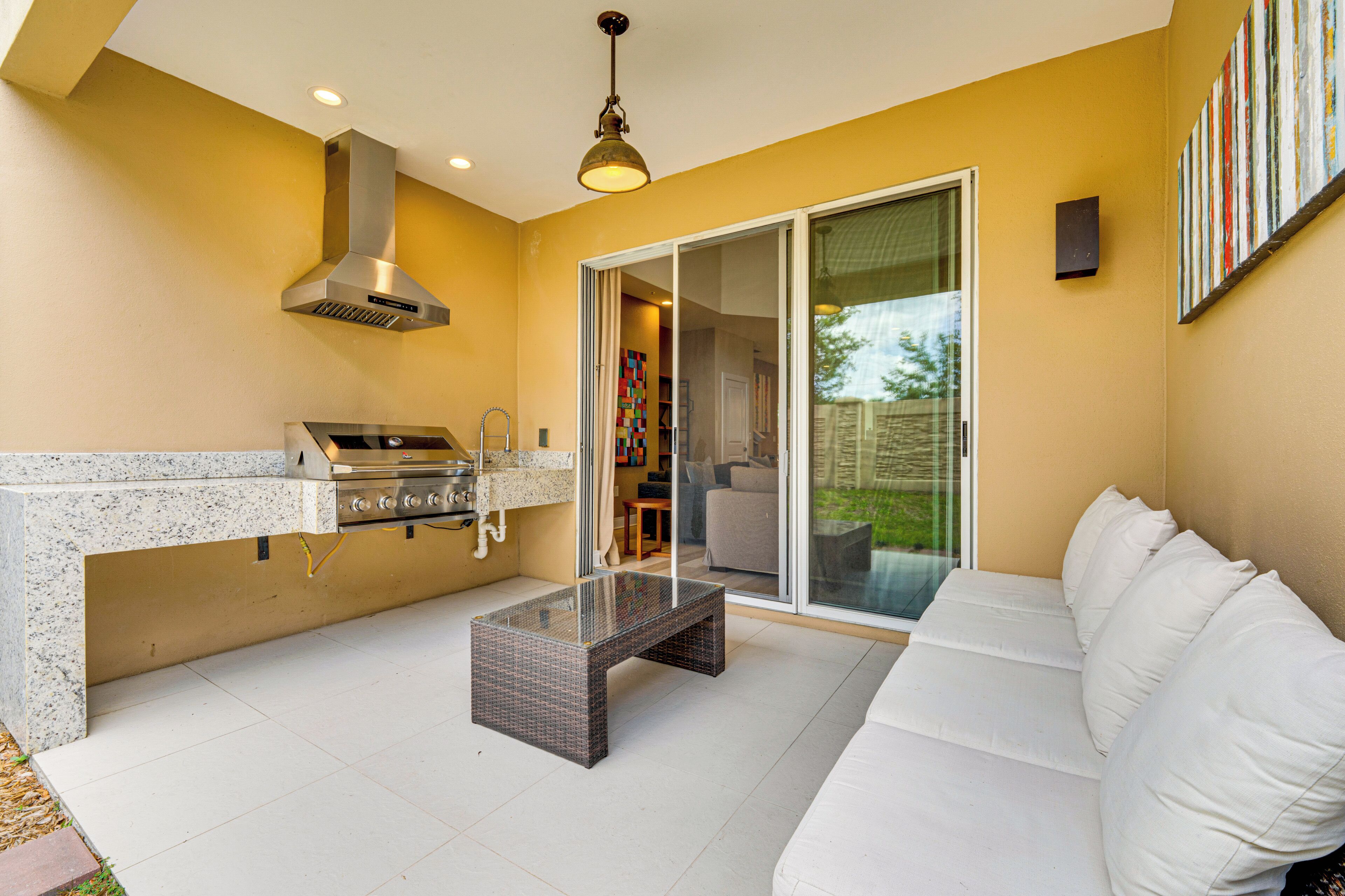A modern kitchen with a built-in grill and a glass sliding door leading to a patio.