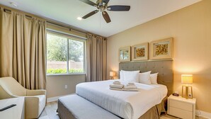 A hotel room with a large bed, a bedside table with a lamp, a chair, and a ceiling fan.