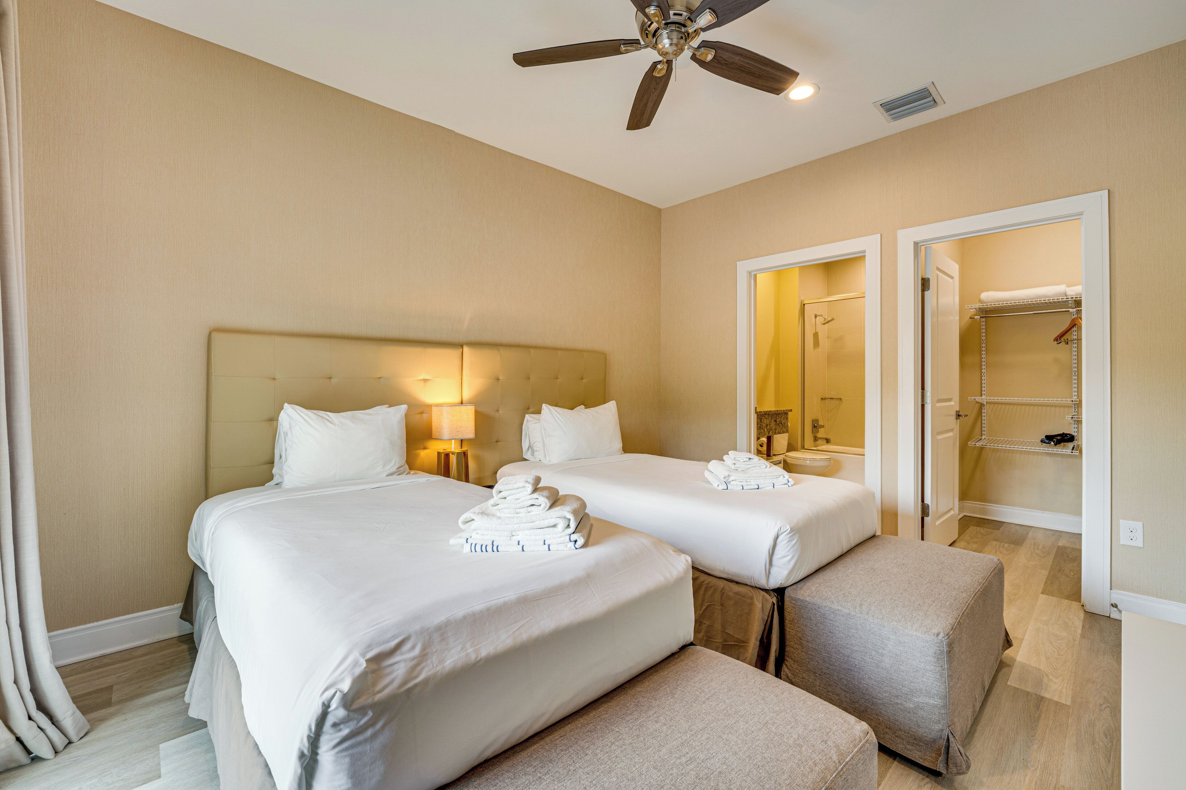 A hotel room with two beds, a ceiling fan, and a bathroom visible through an open door.