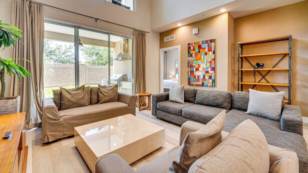 A spacious living room with a large sofa set, a coffee table, and a view of the outdoors.