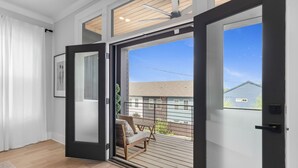 An open sliding glass door leading to a balcony with a wooden deck and a chair. - The Blackstone Manor (Atlanta)