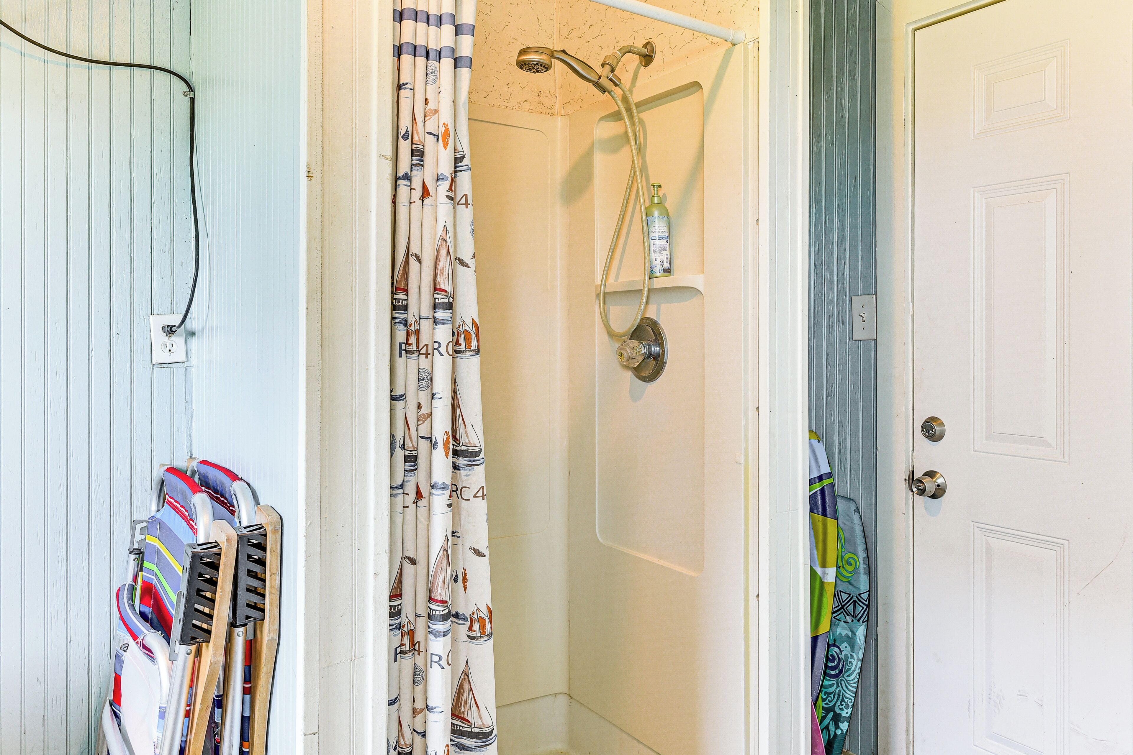 A bathroom with a shower, a towel rack with multiple towels, and a door with a handle.