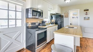 A kitchen with white cabinets, a stainless steel oven, a microwave, and a refrigerator. - Walk to Beach: Galveston Home w/ Patio & Balcony! (Galveston)