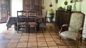 Un coin repas avec une table en bois, des chaises et un lustre. On y trouve également une grande armoire en bois et un vase décoratif accroché au mur.