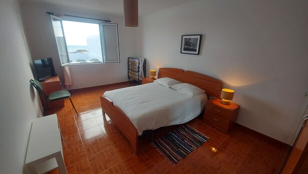 A bedroom with a bed, bedside tables, a television, a window, and a picture on the wall. - Lagoa SEA View by Vacationy (Lagoa)