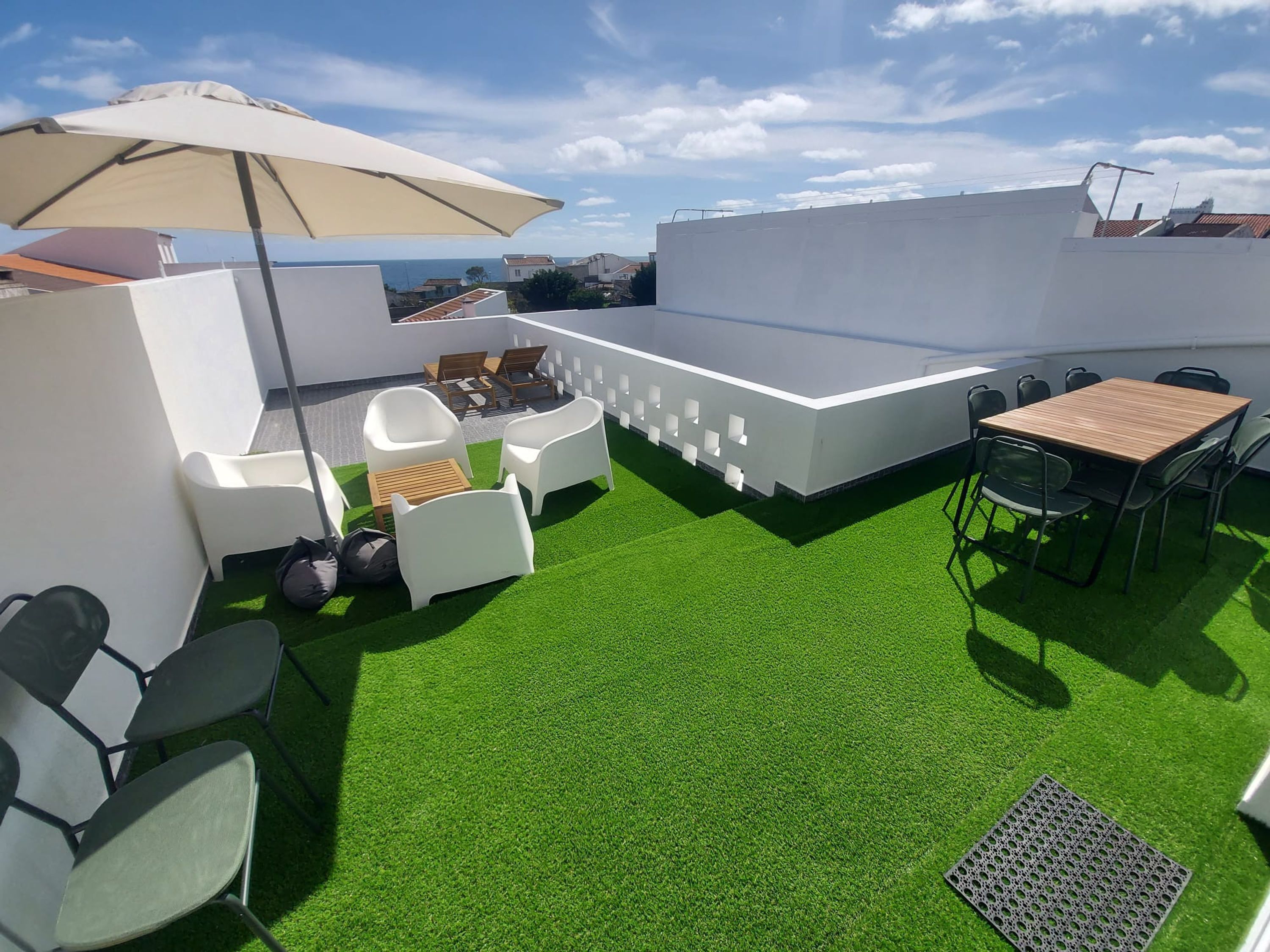 Une terrasse sur le toit, dotée d’un revêtement d’herbe artificielle, de mobilier d’extérieur et d’une table avec des chaises.
