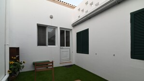 A small, enclosed outdoor space with a white wall, a wooden bench, a door, and a window with shutters. - Lagoa SEA View by Vacationy (Lagoa)