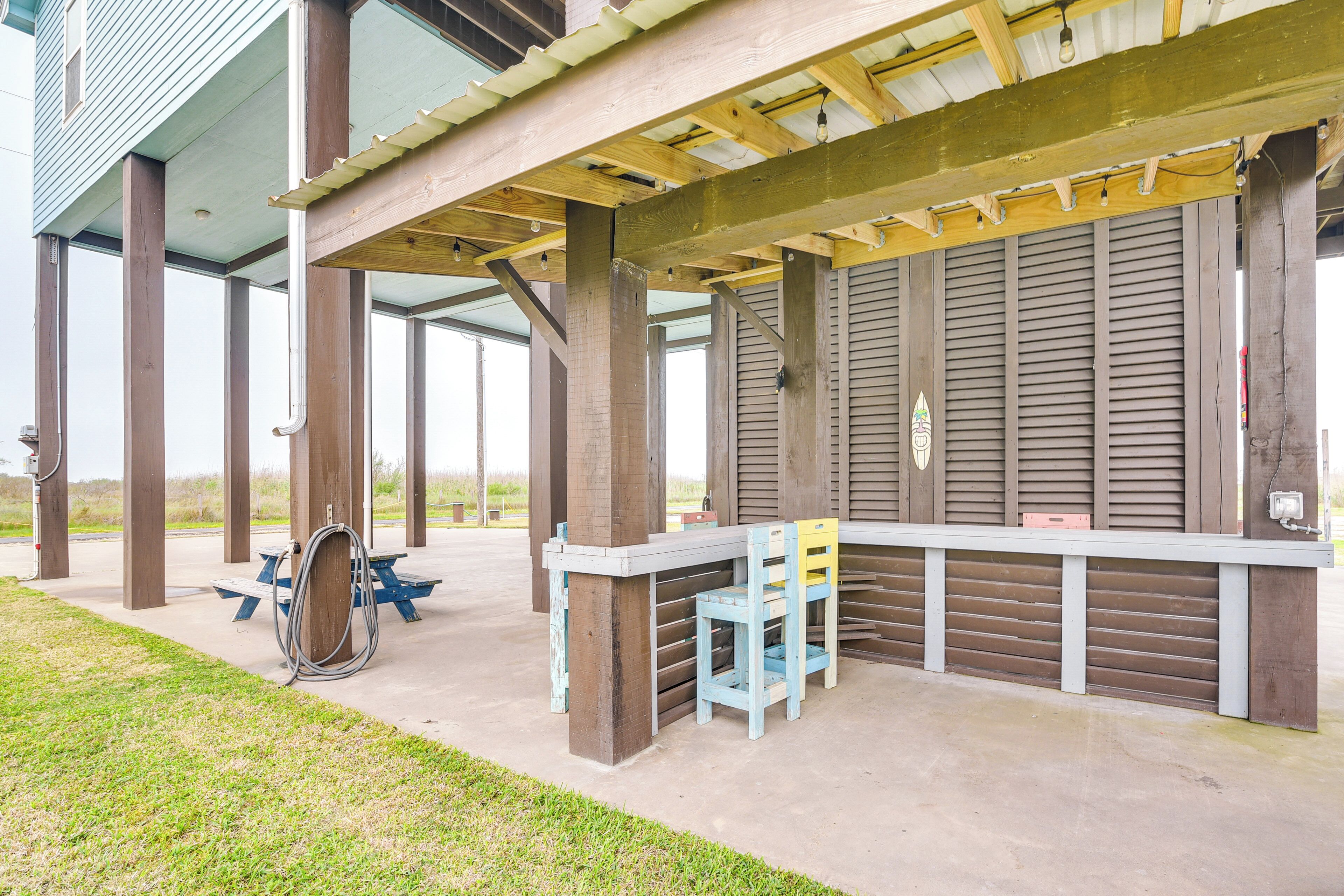 Un'area patio esterna con una pergola in legno, tavolo da picnic e sedie.