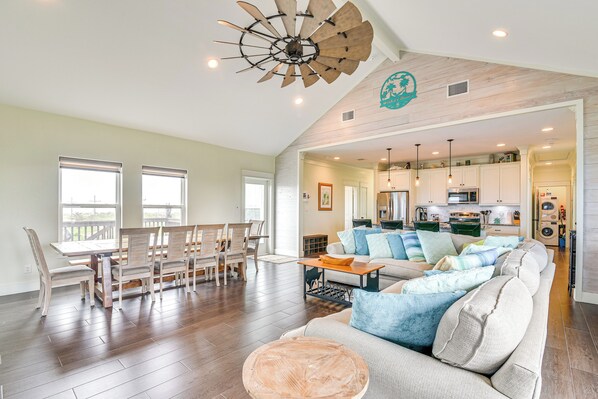 A spacious living area with a dining table, chairs, a sofa, and a ceiling fan.