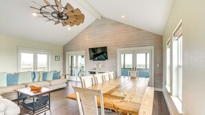 Un vaste espace de vie comprenant une grande table à manger en bois, un canapé et un ventilateur de plafond.