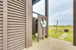 A wooden building with a slatted exterior and a concrete pathway leading to a grassy area.