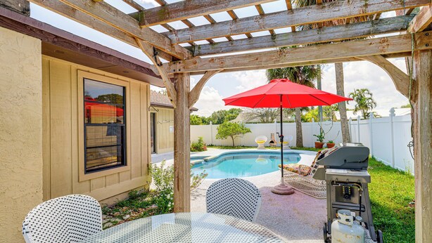 Eine Terrasse mit Pool, Gartenmöbeln und Grill.
