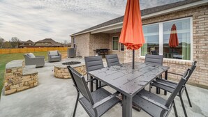 Eine Terrasse im Freien mit einem Steinkamin, einem Tisch mit Stühlen und einem Sonnenschirm.