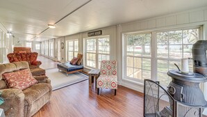 A spacious room with a large window, a cozy fireplace, and a sign that reads "HAPPY HOUR". - Walk to Beach: Eufaula 'fishermans Delight' Home (Eufaula)