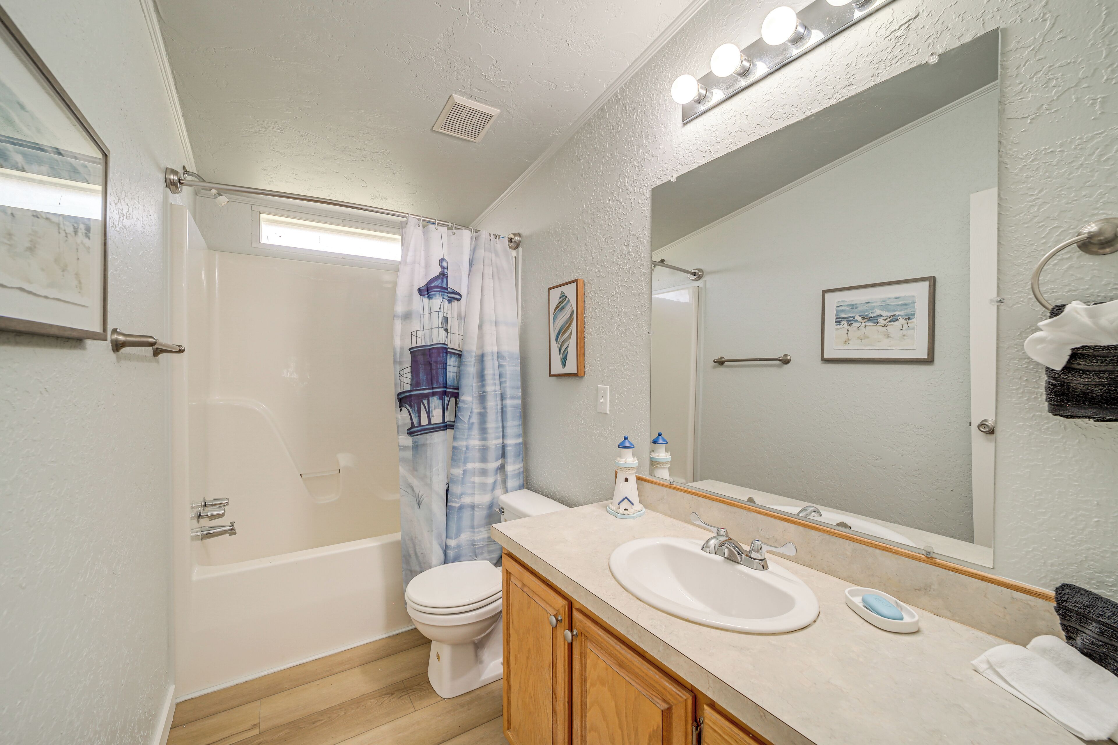 A bathroom with a bathtub, toilet, sink, and a large mirror.