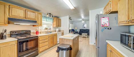 A modern kitchen with wooden cabinets, stainless steel appliances, and a central island.