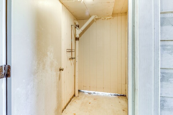 A narrow, enclosed bathroom with white walls and a white floor, featuring a visible pipe and a metal rack. - Close to Coastal Beaches & Bay Side to Sound (Kill Devil Hills)