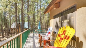 A wooden deck with a green railing, surrounded by tall pine trees. - Walk to Lake & Trails: Angel Fire Home w/ Deck! (Angel Fire)