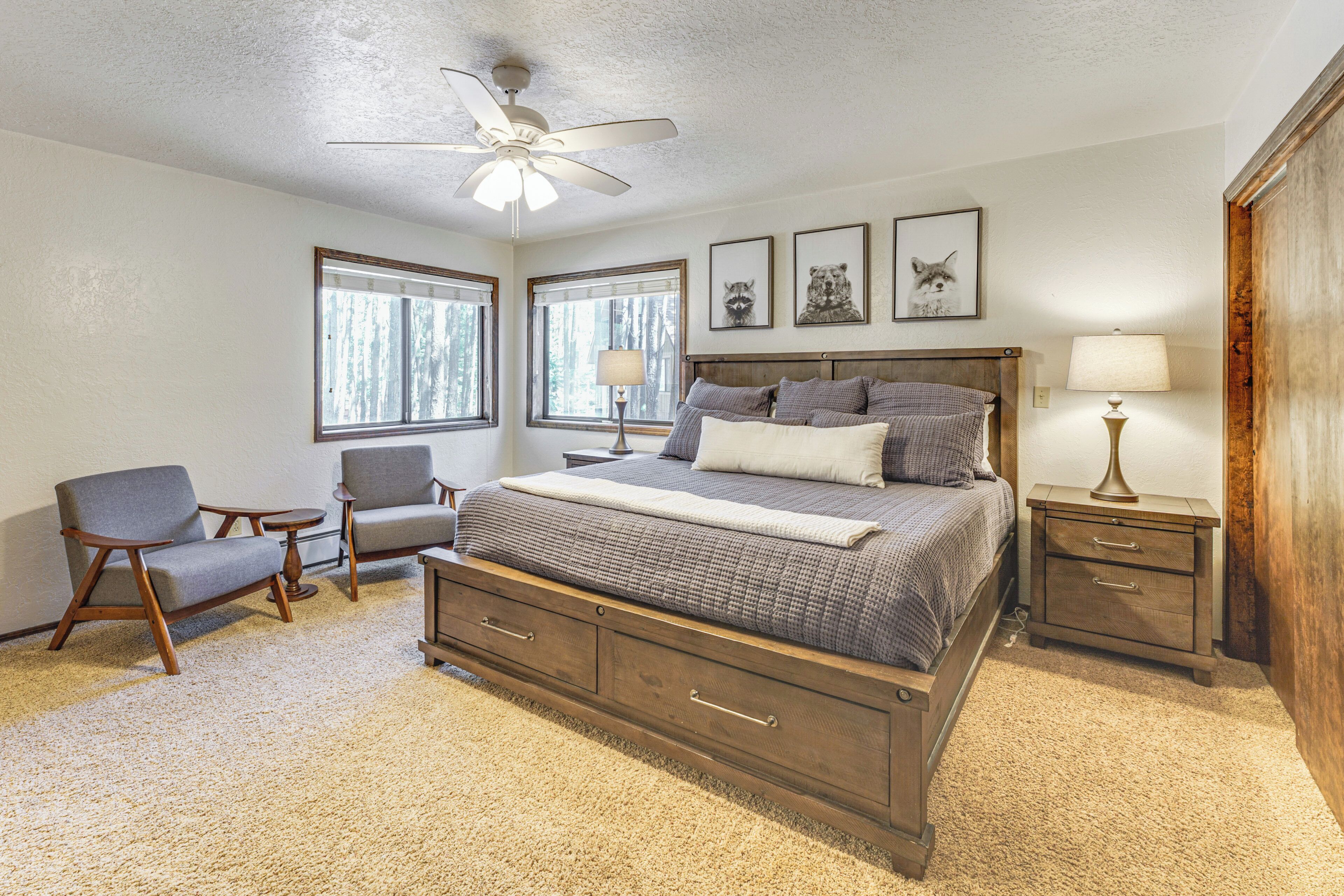 A bedroom with a large bed, two bedside tables, a chair, and a ceiling fan.