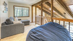 A room with a sloped ceiling, a sofa, a window, and a view of the outdoors. - Walk to Lake & Trails: Angel Fire Home w/ Deck! (Angel Fire)