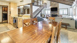 A spacious living area with a wooden dining table, a staircase, and a fireplace. - Walk to Lake & Trails: Angel Fire Home w/ Deck! (Angel Fire)