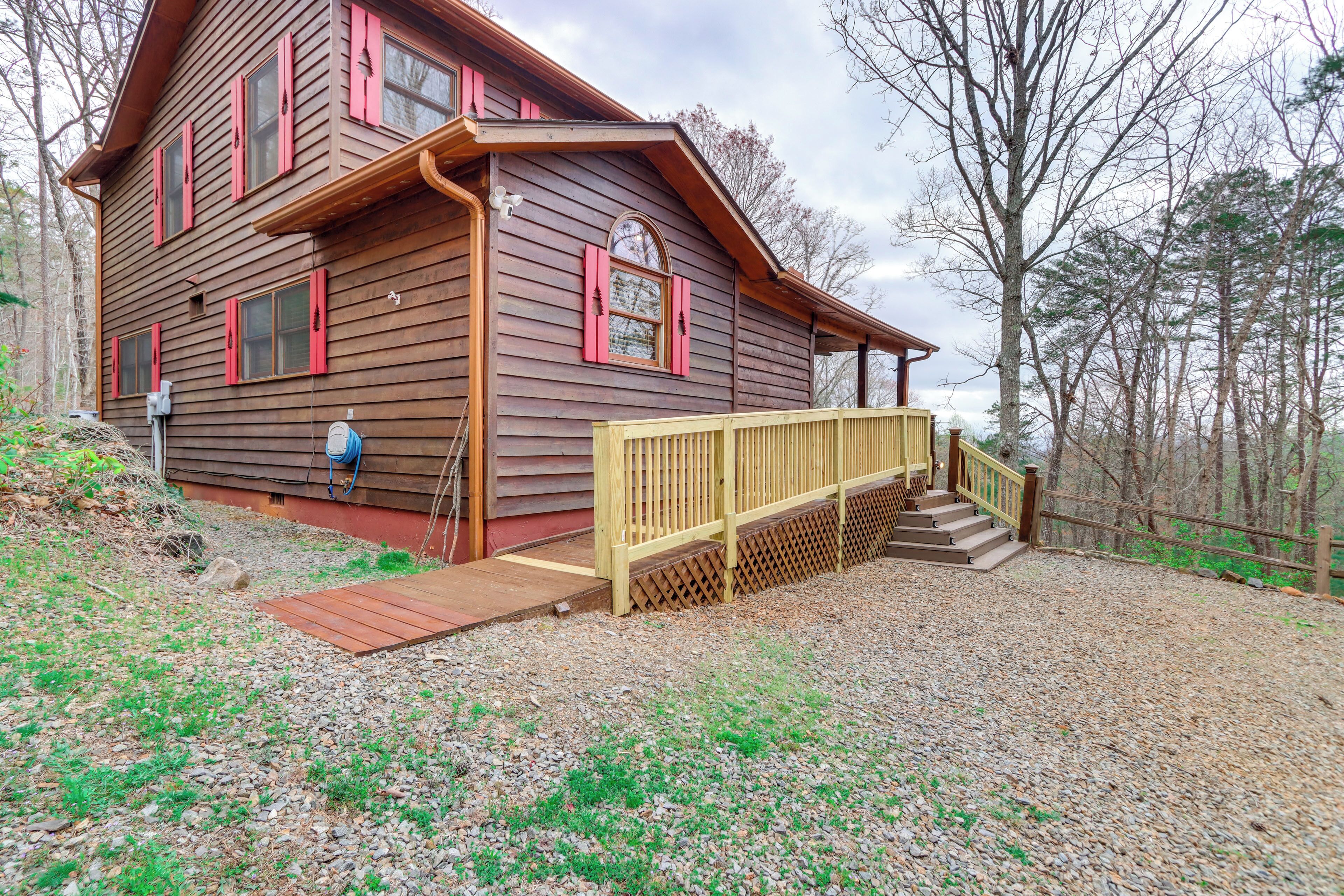 A wooden cabin with a porch and steps leading to a deck.