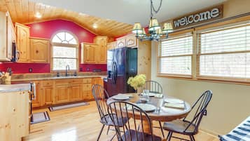 A kitchen with wooden cabinets, a black refrigerator, and a dining table set for four.